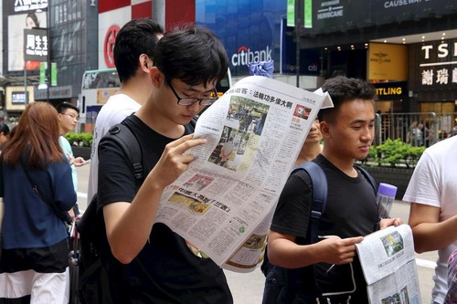 Китайські туристи читають газети Фалуньгун