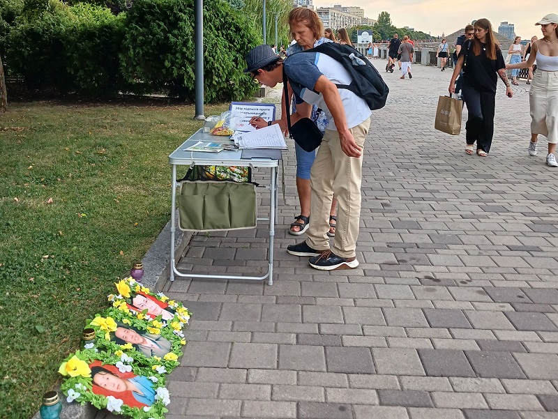 Під час заходу в Дніпрі люди підписують петицію, яка закликає зупинити переслідування, яке здійснює компартія Китаю